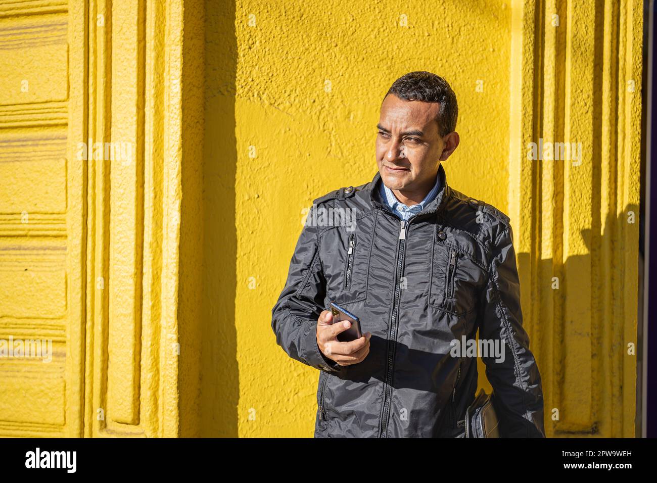 Portrait of a young latino man over a yellow wall with copy space. Stock Photo