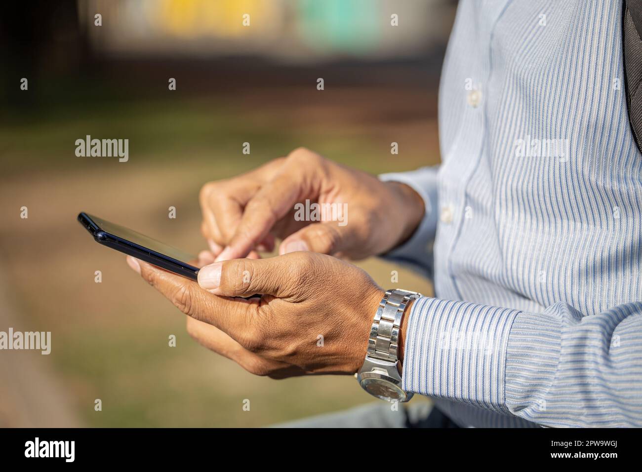 Detail of the hands of a Latino man using a mobile phone. Stock Photo