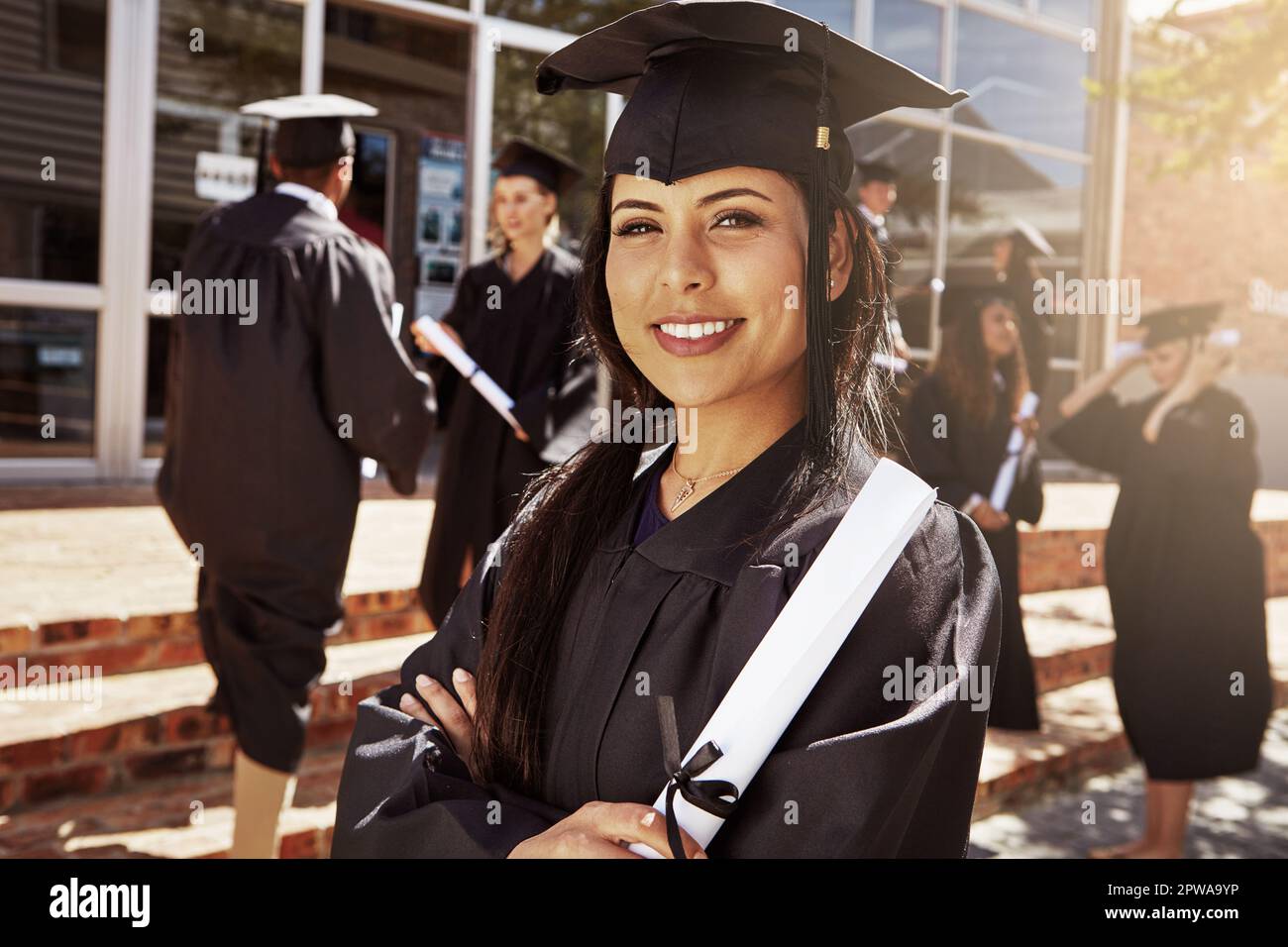 I studied hard to get here today. Portrait of a smiling university student holding her diploma outside on graduation day. Stock Photo