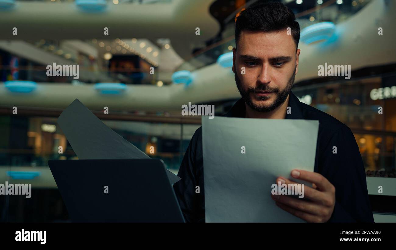 Male young businessman entrepreneur man doing corporate paperwork read business contract documentation paying bank loan bills online in banking app Stock Photo