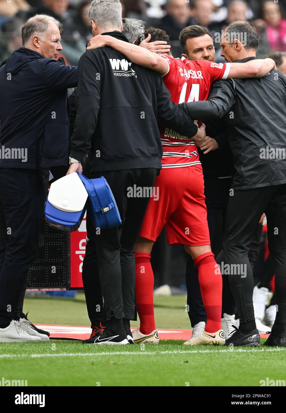 29 April 2023, Hesse, Frankfurt/Main: Soccer: Bundesliga, Eintracht Frankfurt - FC Augsburg, Matchday 30, Deutsche Bank Park. Stefan Reuter (l), Managing Director Sport, and Augsburg's head coach Enrico Maaßen (2nd from right) check on injured player Julian Baumgartlinger. Photo: Arne Dedert/dpa - IMPORTANT NOTE: In accordance with the requirements of the DFL Deutsche Fußball Liga and the DFB Deutscher Fußball-Bund, it is prohibited to use or have used photographs taken in the stadium and/or of the match in the form of sequence pictures and/or video-like photo series. Stock Photo