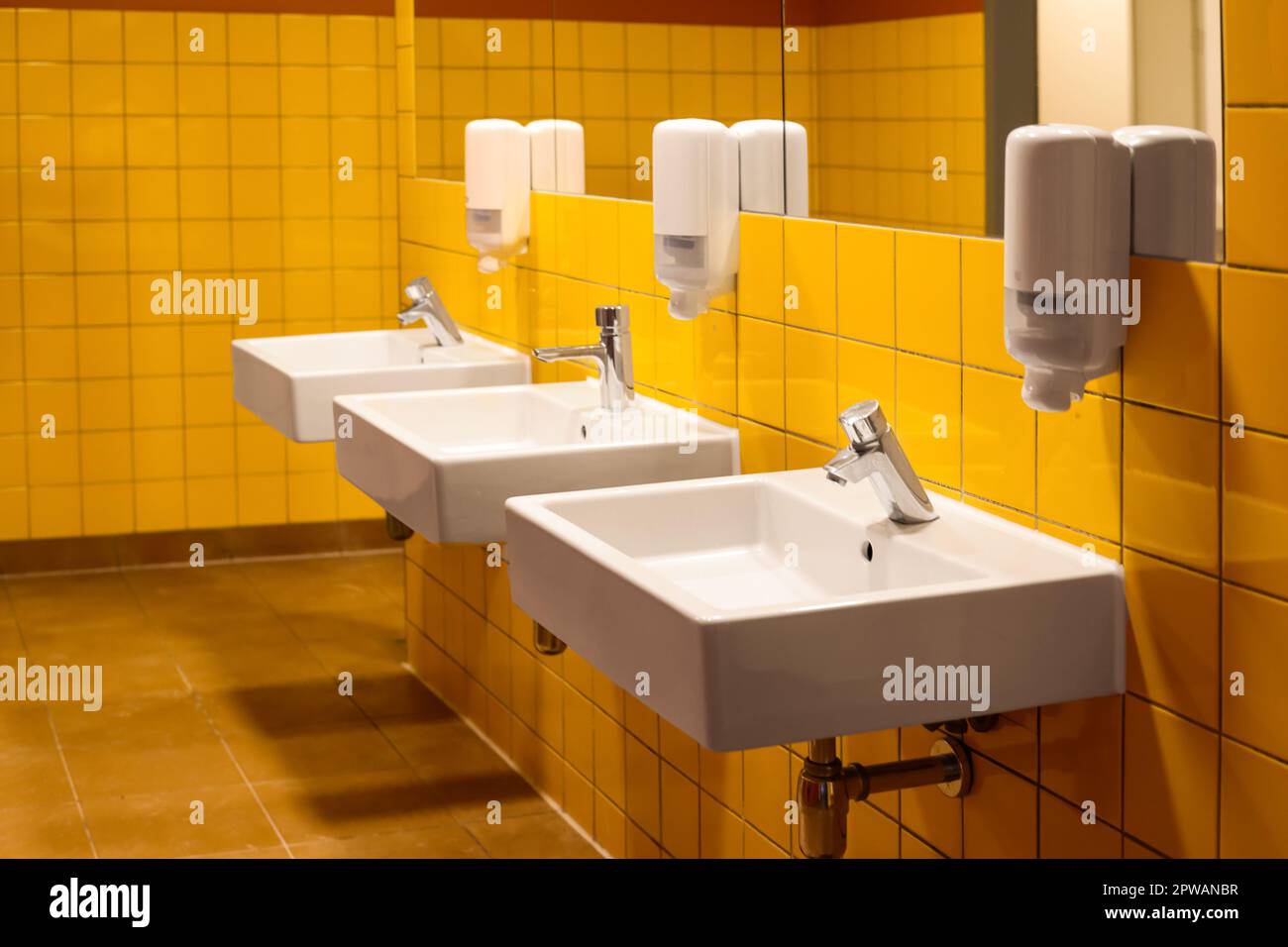 View of sinks with automatic soap dispensers in public restroom Stock