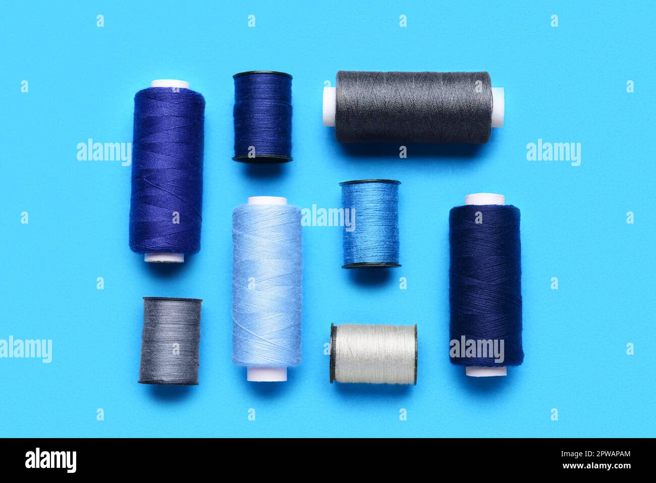 Composition with different thread spools on color background Stock Photo