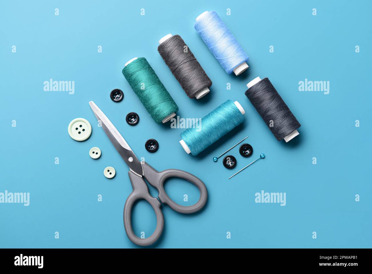 Composition with thread spools, buttons, scissors and ball pins on color background Stock Photo