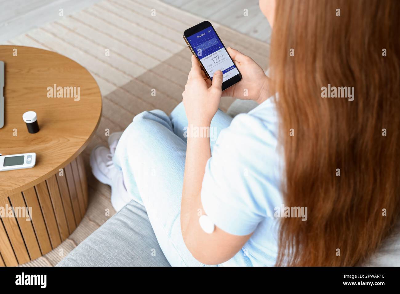 Woman with glucose sensor using mobile phone for measuring of blood