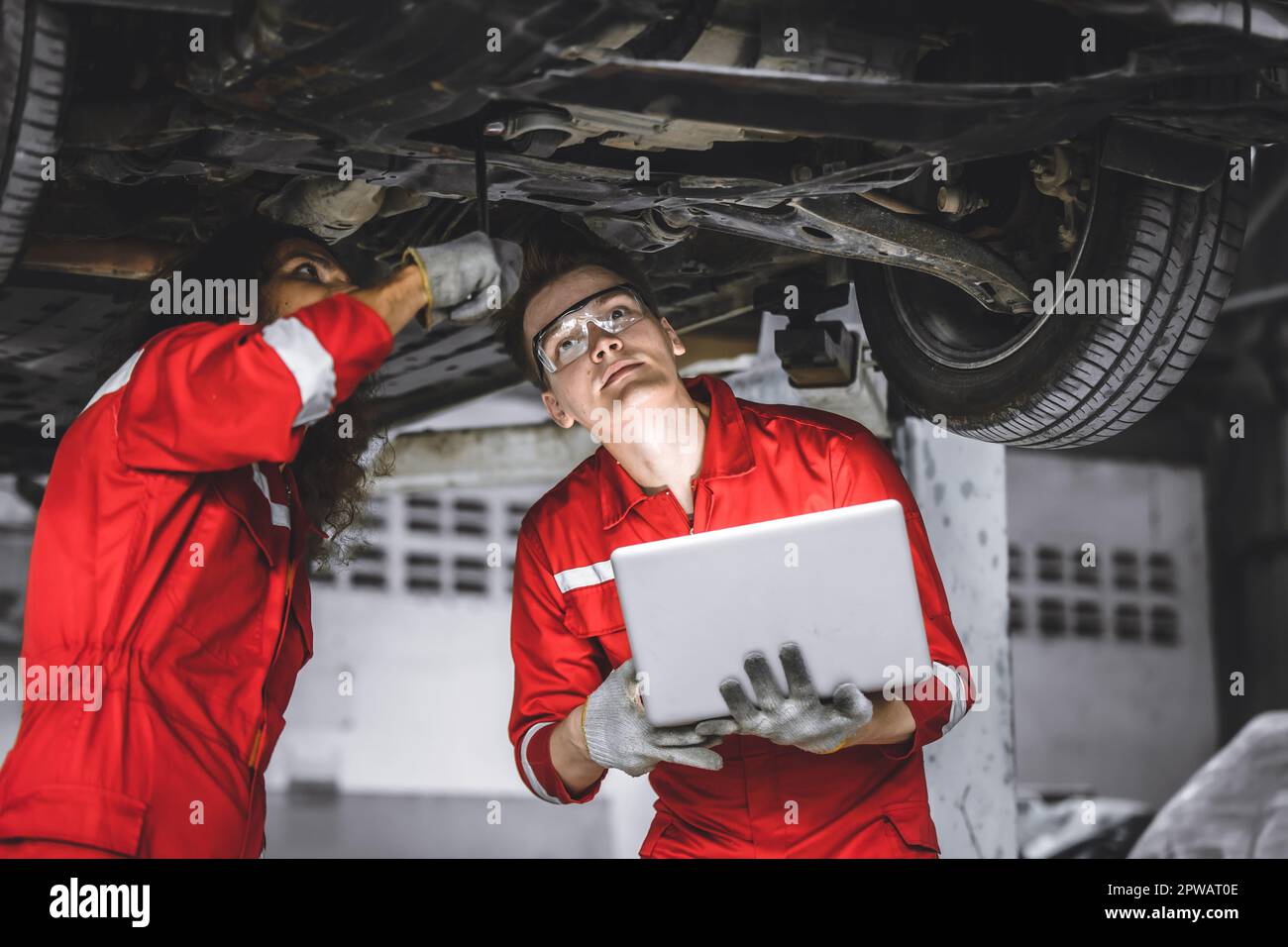 Mechanic male team staff worker working together under car auto service check tuning in garage Stock Photo