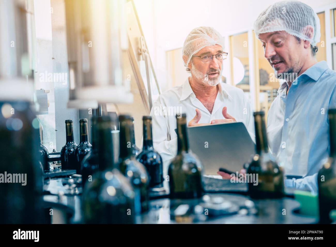Food production process inspector team working in beverage bottle conveyor line Stock Photo