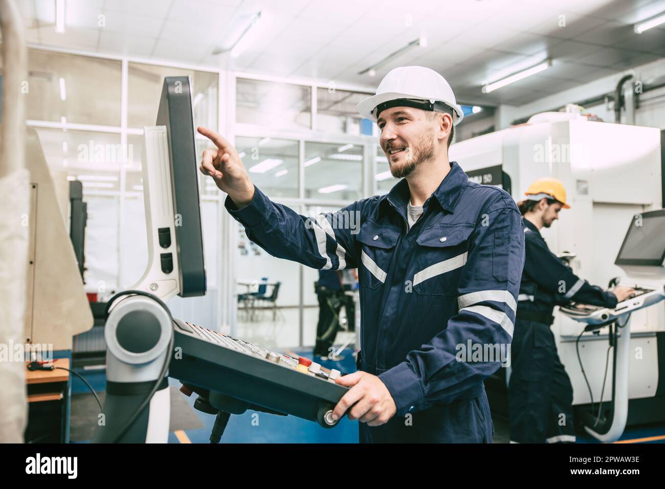 CNC Lathe Machine Engineer Operator Worker Working Entering Work Batch Production Program Data at Heavy Metal Factory Stock Photo