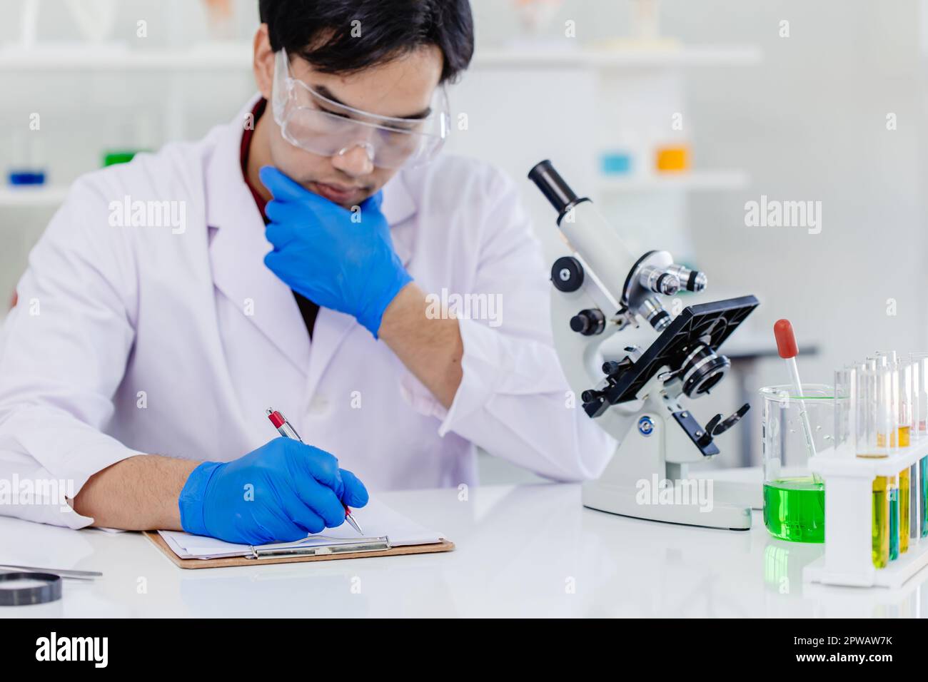 Young Asian scientist man wearing white lab uniform testing research medical formula at laboratory Stock Photo