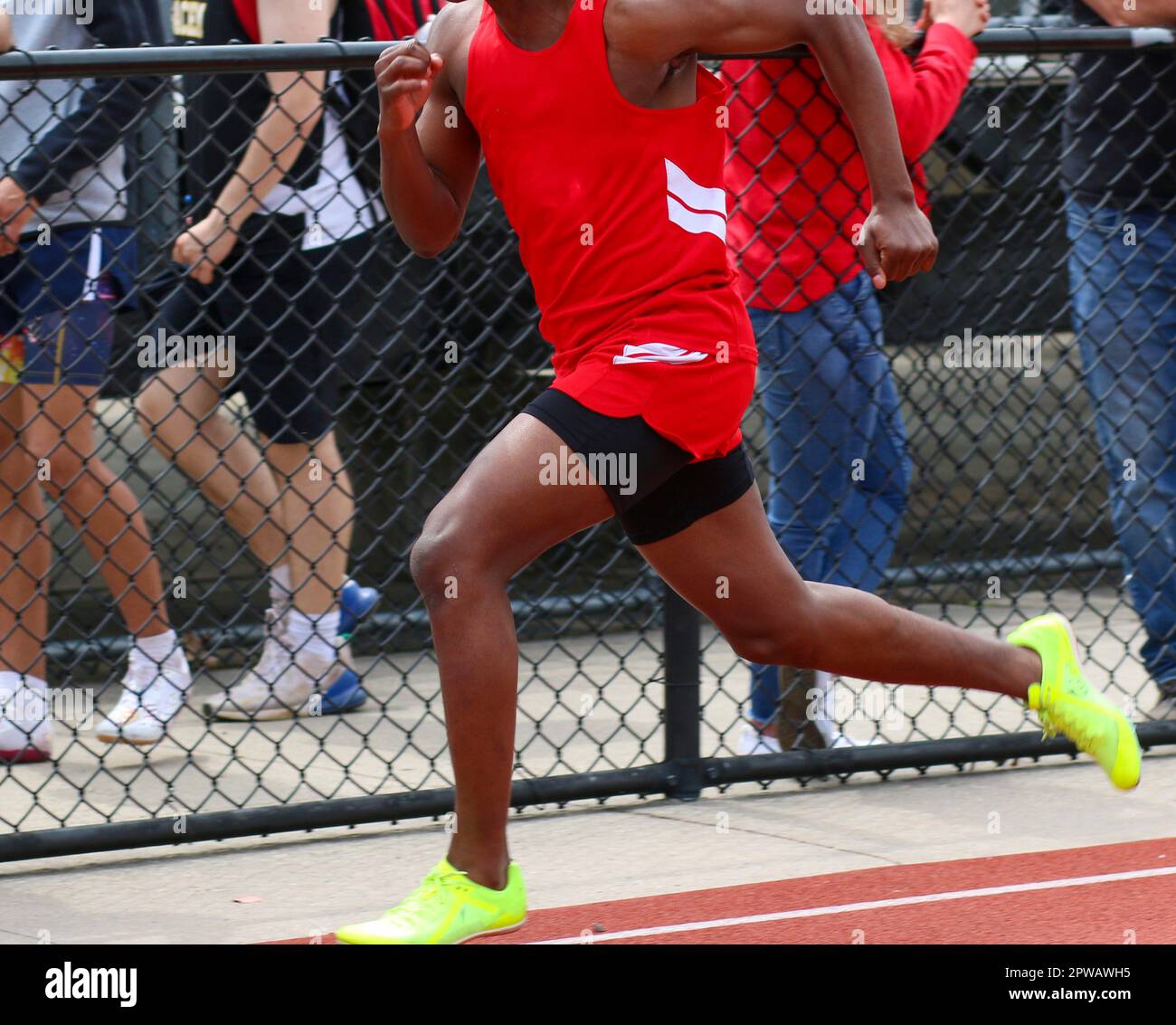 A high school boy is running in the 100 meter dash during a track and