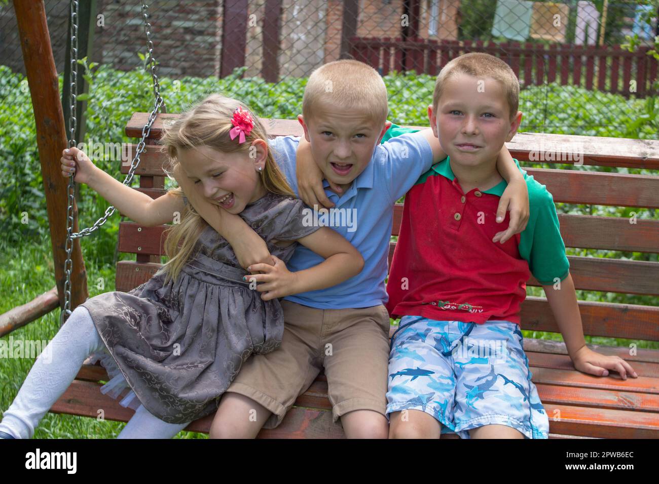 girl and two boys lay on stomach on the green grass and eat apples Stock Photo