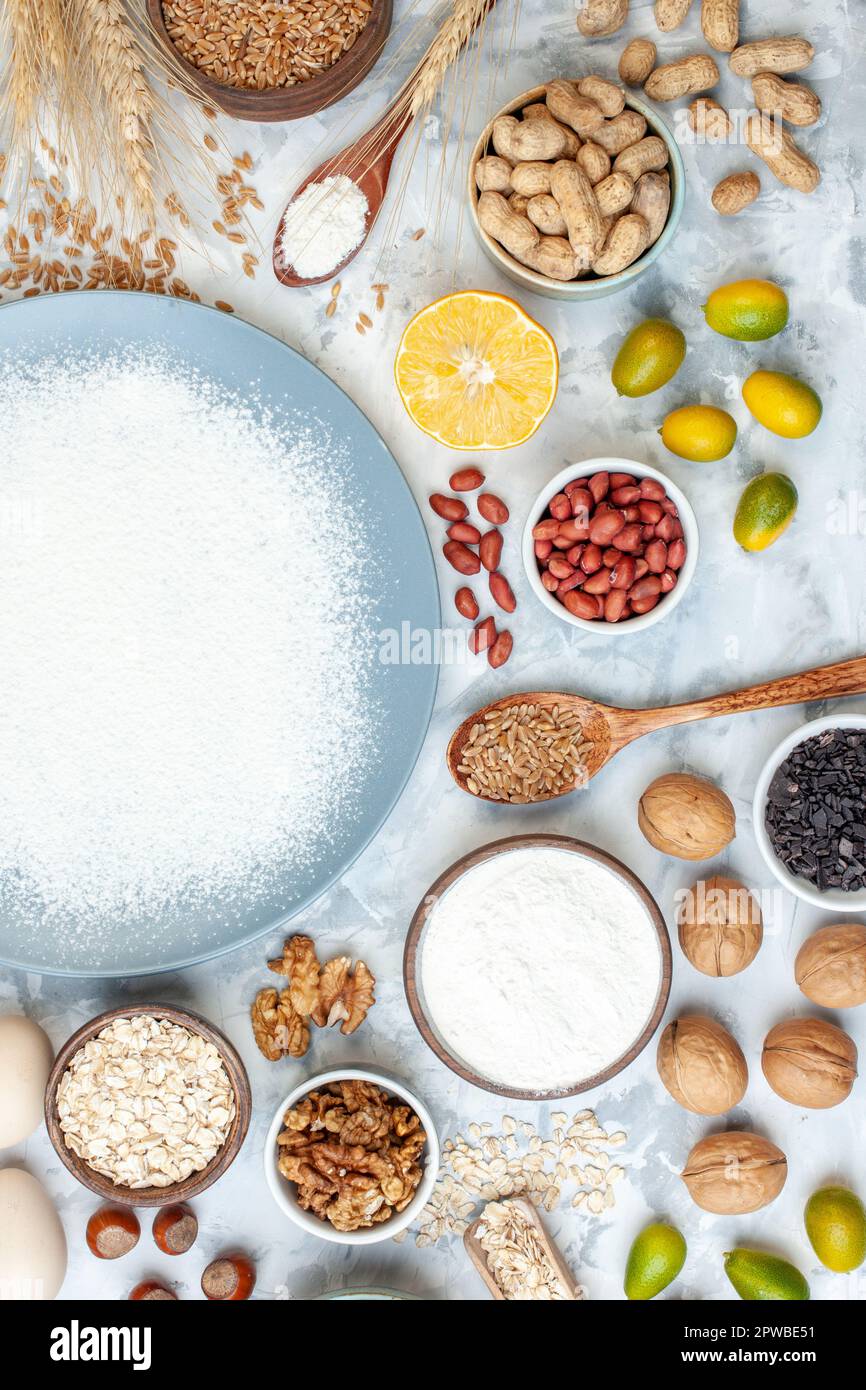 top view white flour inside plate with nuts seeds and eggs on white