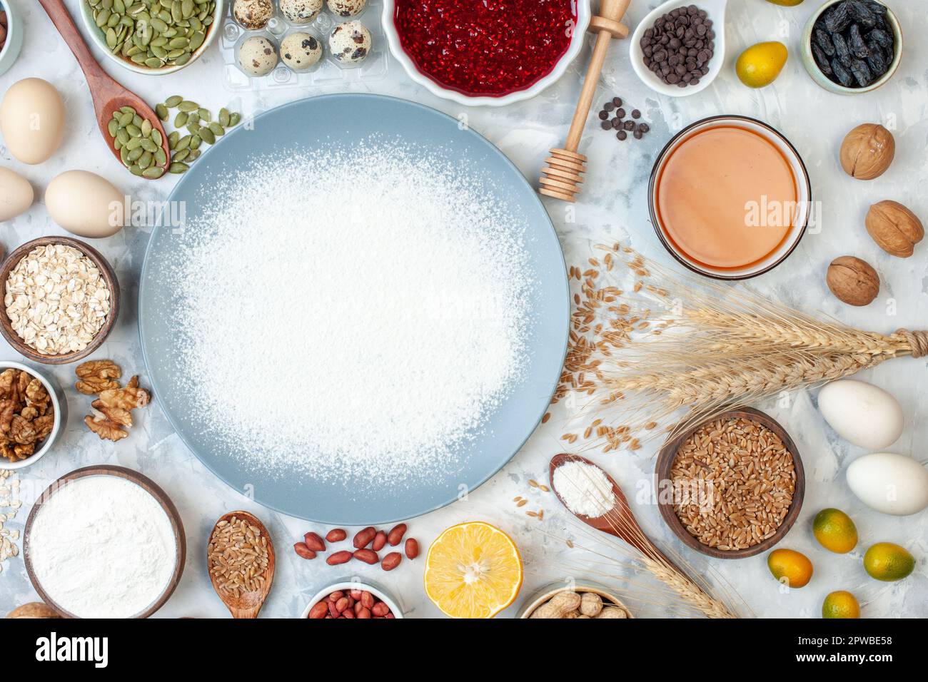 top view white flour inside plate with nuts seeds and eggs on white