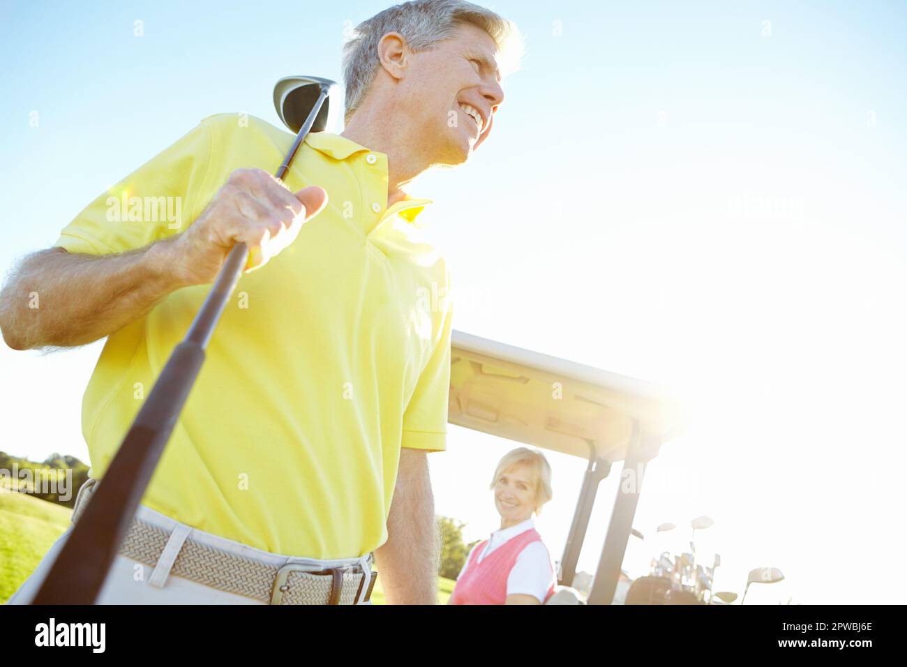 Golfing is the perfect pastime. Low angle shot of a handsome older golfer standing in front of a golf cart with his golfing buddy behind the wheel. Stock Photo