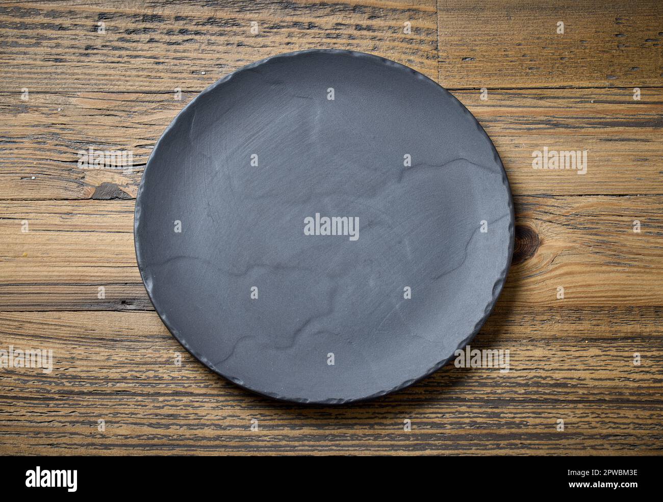 empty black plate on wooden kitchen table, top view Stock Photo