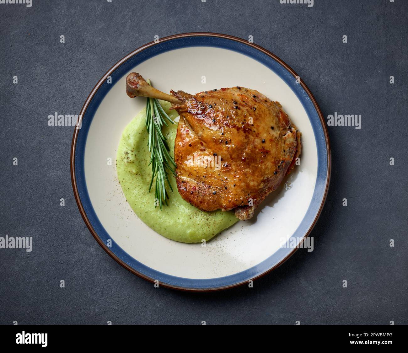 plate of duck leg confit and broccoli puree, top view Stock Photo