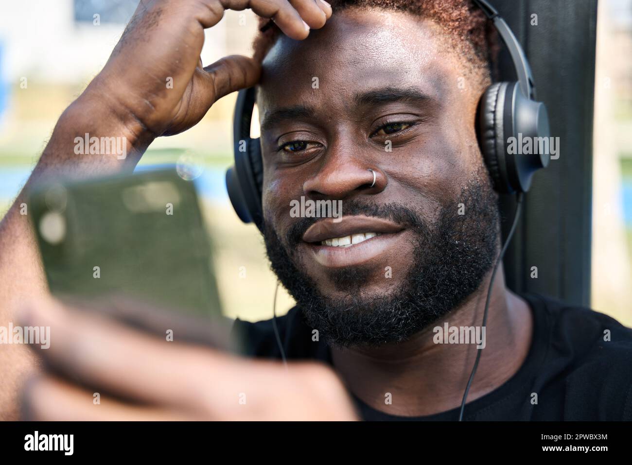 Fit sporty young black man using phone listening music during street workout. Stock Photo
