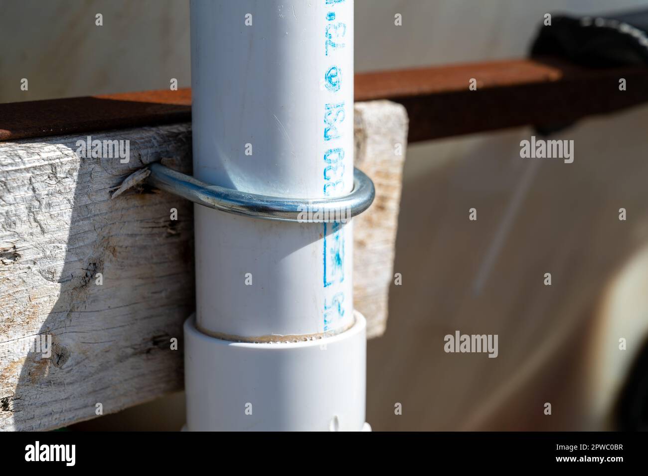 Vertical installation of a PVC pipe in an agricultural setting showing a clamp fastener Stock