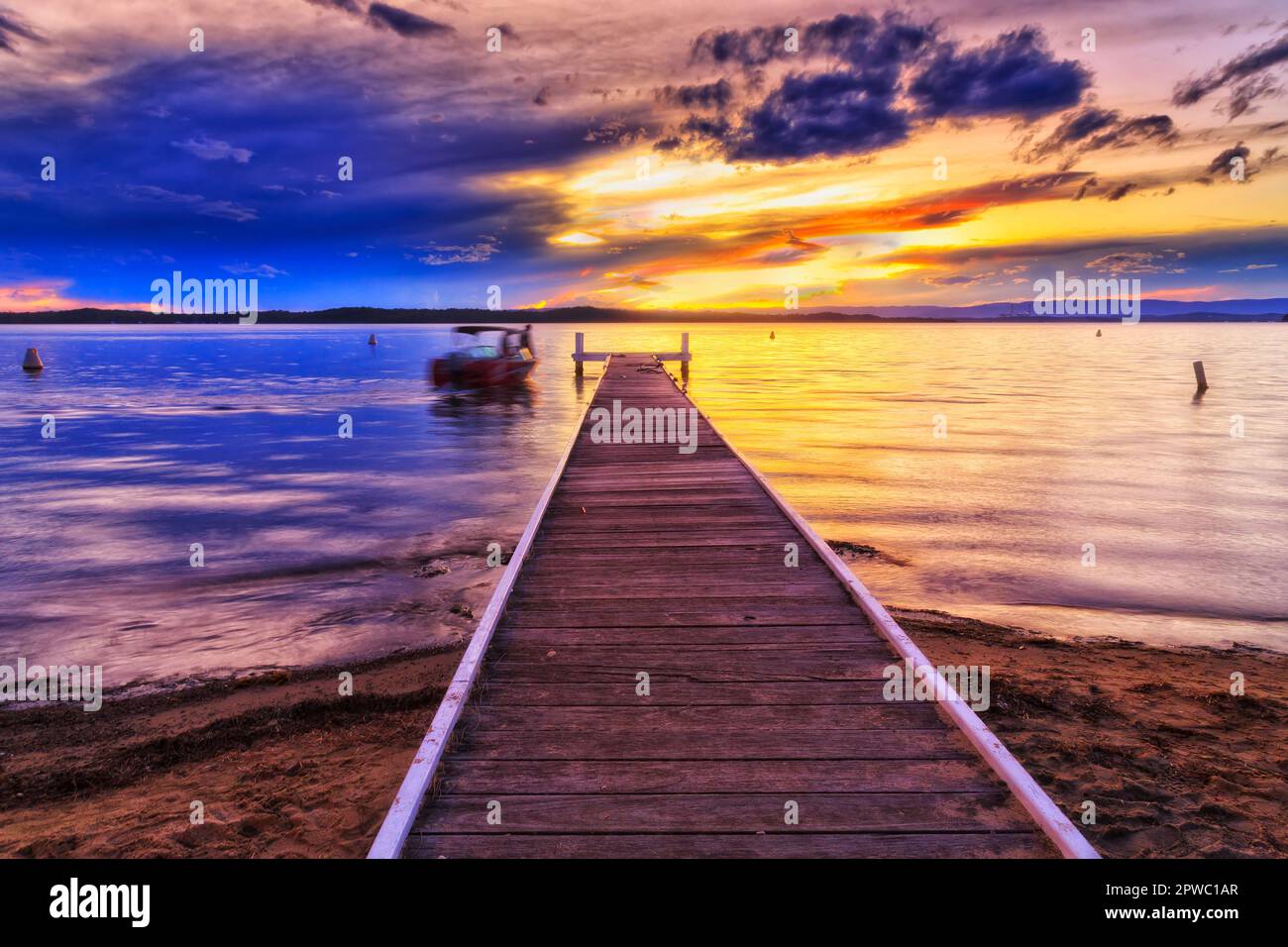 Fishing boat floating at timber jetty off Murrays beach resort beach on