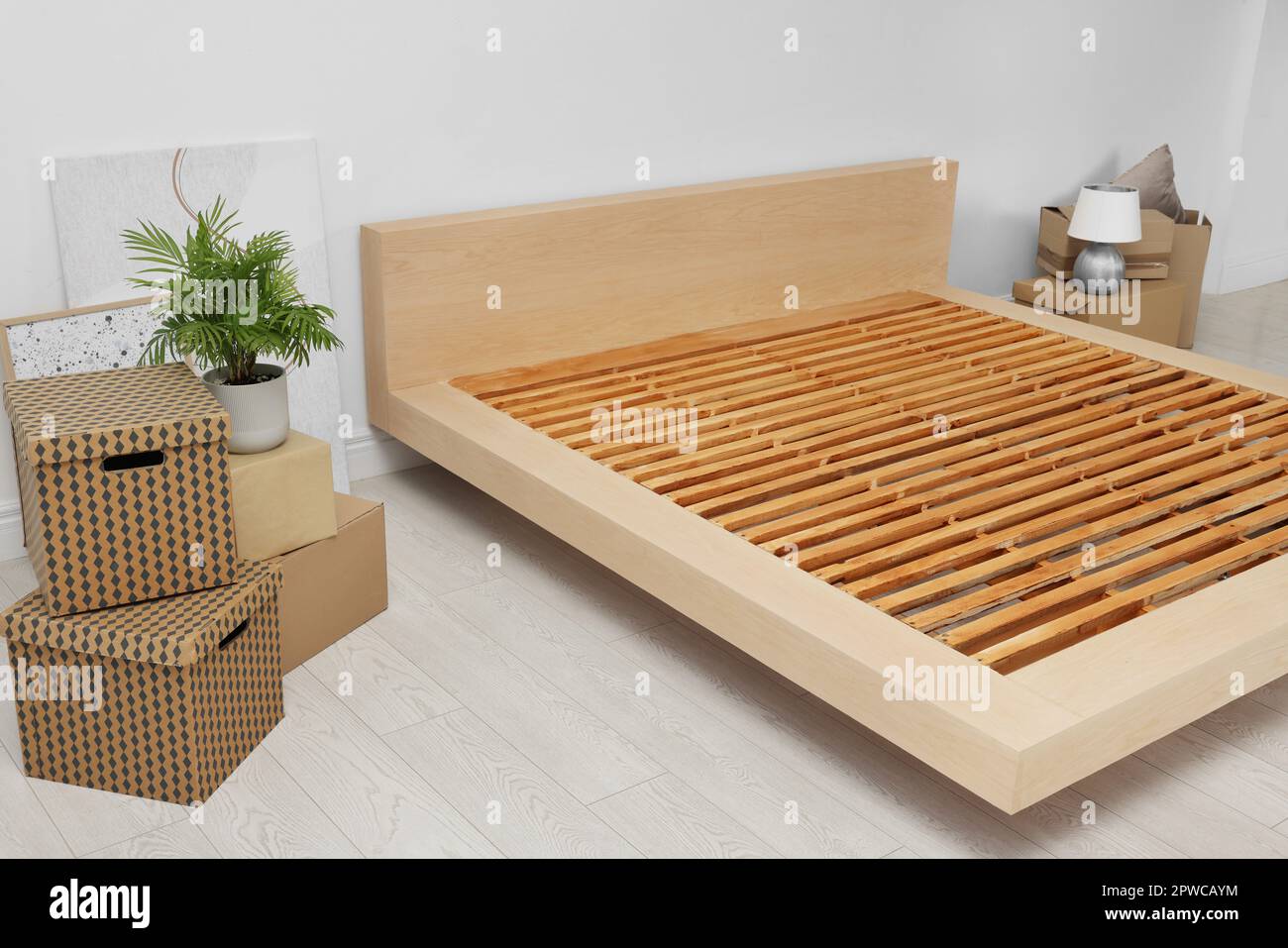 New wooden bed frame, moving boxes and decor elements indoors Stock