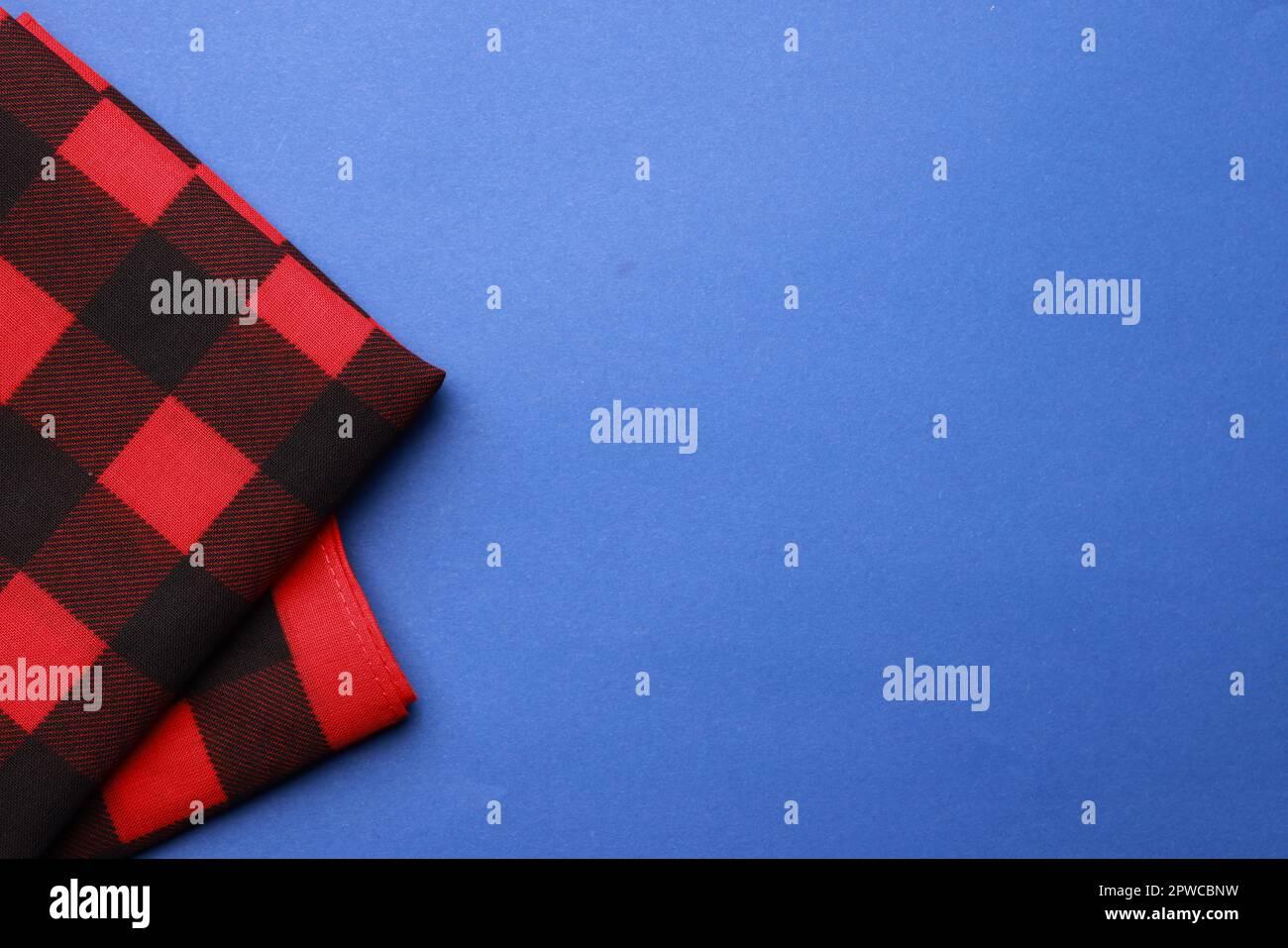 Folded red bandana with check pattern on blue background, top view. Space for text Stock Photo