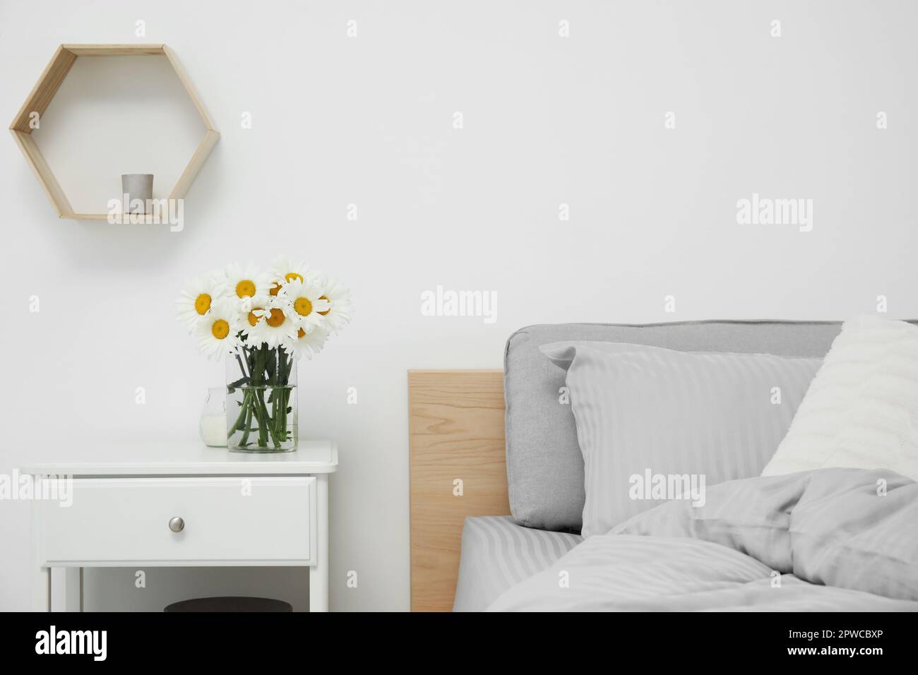 Bouquet of beautiful daisy flowers on nightstand in bedroom Stock Photo