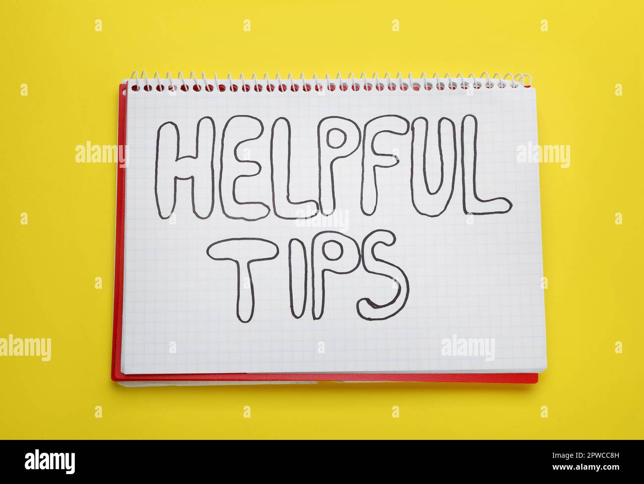 Phrase Helpful Tips in notebook on yellow background, top view Stock Photo