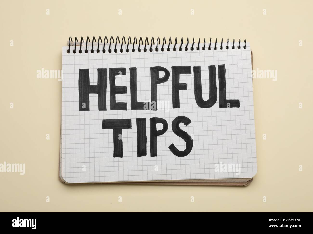 Phrase Helpful Tips in notebook on beige background, top view Stock Photo