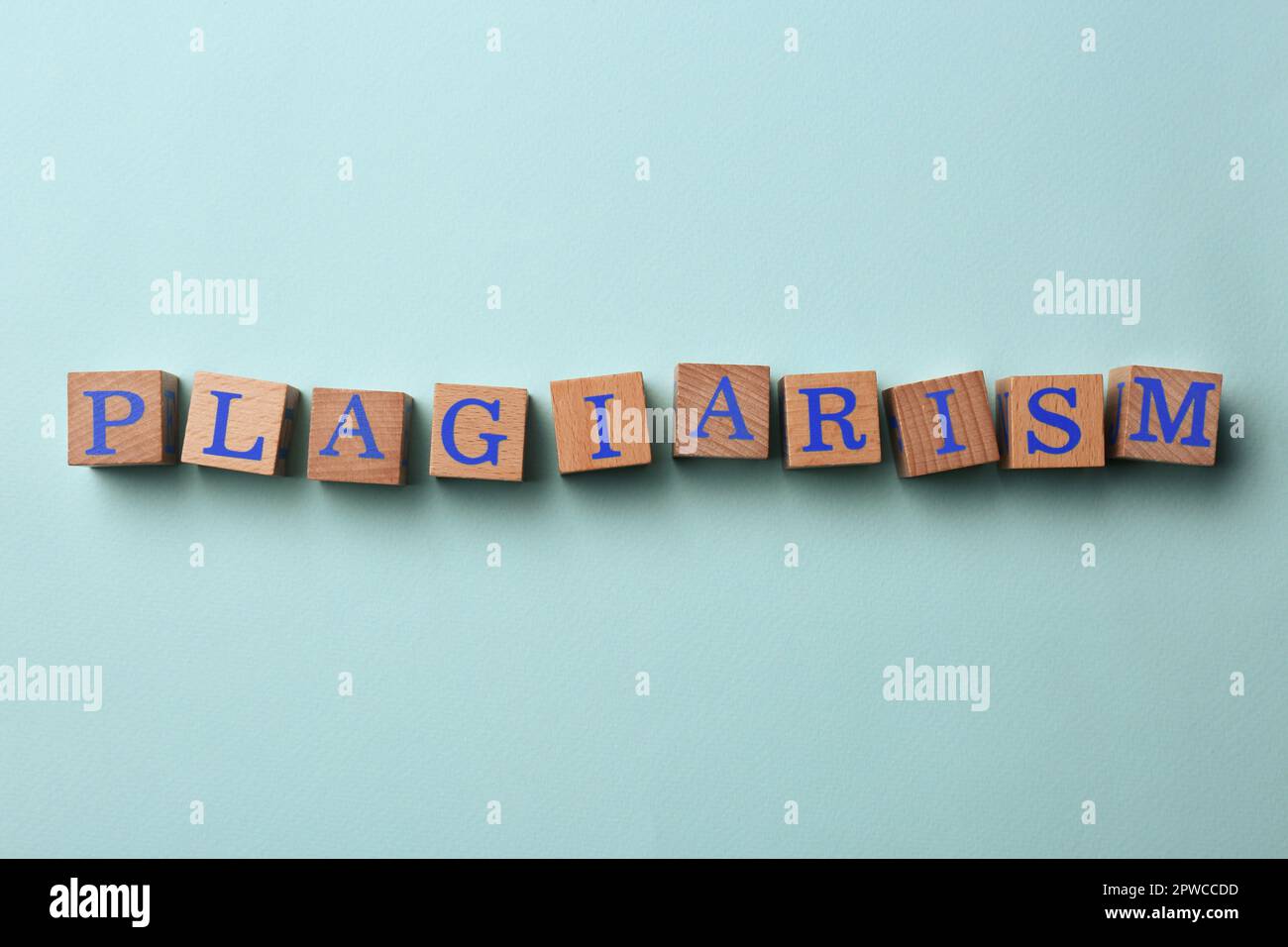 Wooden cubes with word Plagiarism on turquoise background, flat lay ...