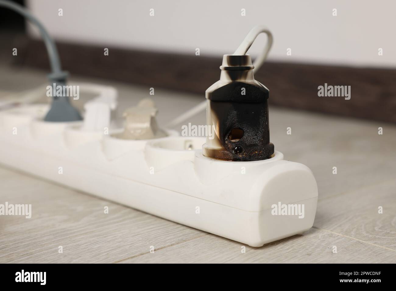Burnt plug in power strip indoors, closeup. Electrical short circuit