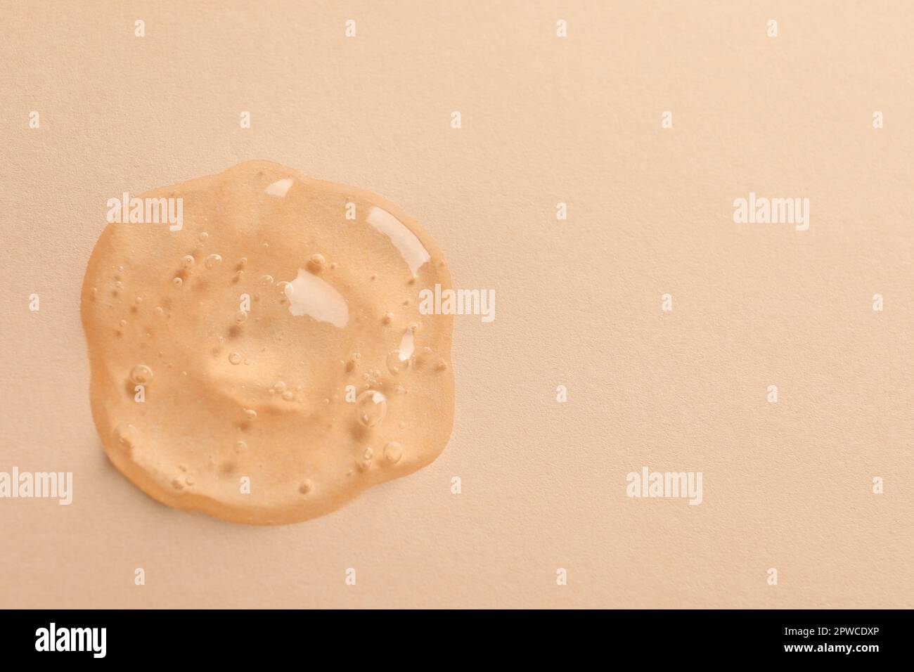 Sample of face gel on pale orange background, top view. Space for text ...