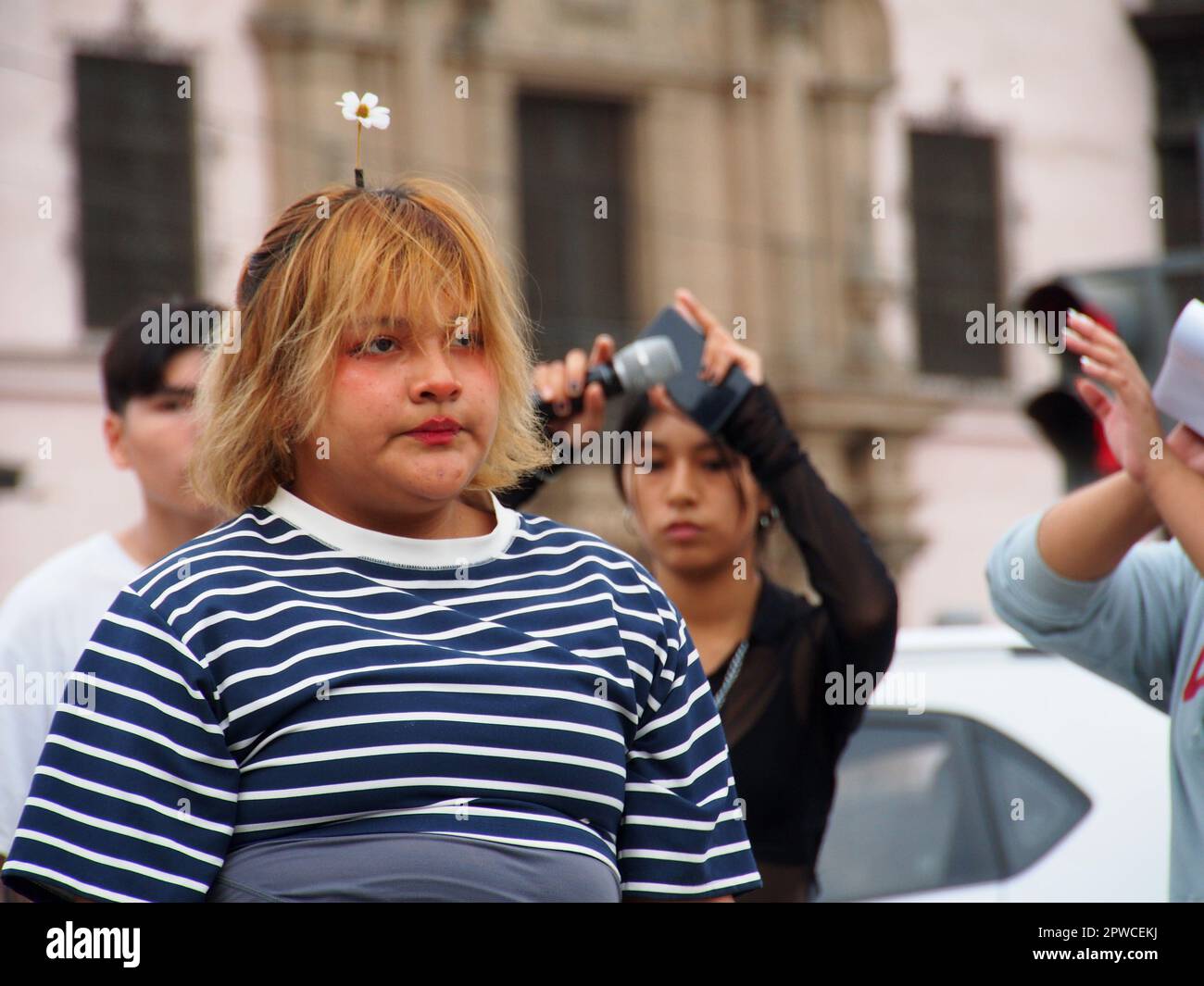 A woman with a small flower on her head when followers of Korean Pop culture (K-pop) dance choreographies of their favorite groups in the streets of Lima downtown,  as part of an spontaneous flash mob on International Dance Day. International Dance Day is celebrated worldwide every April 29. Stock Photo