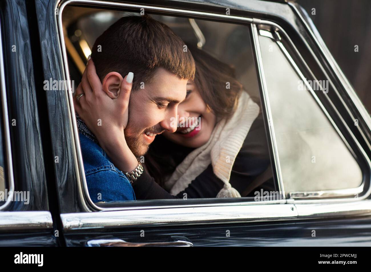 Loving man and woman hugging in retro car in park Stock Photo