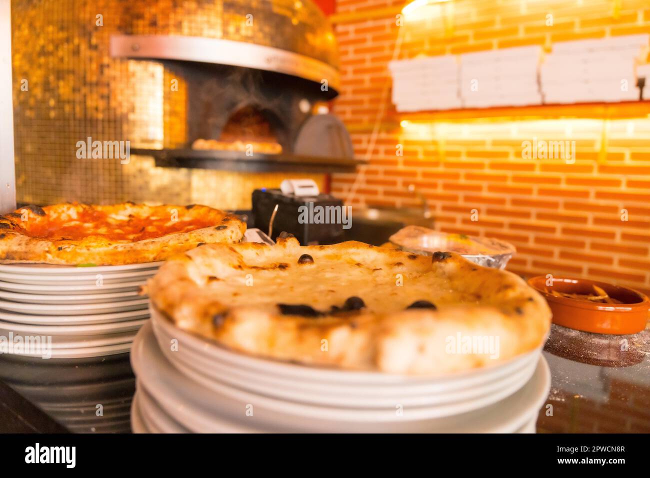 Artisan pizza oven. Freshly made pizza coming out of the oven, pizza hot and ready for customers Stock Photo