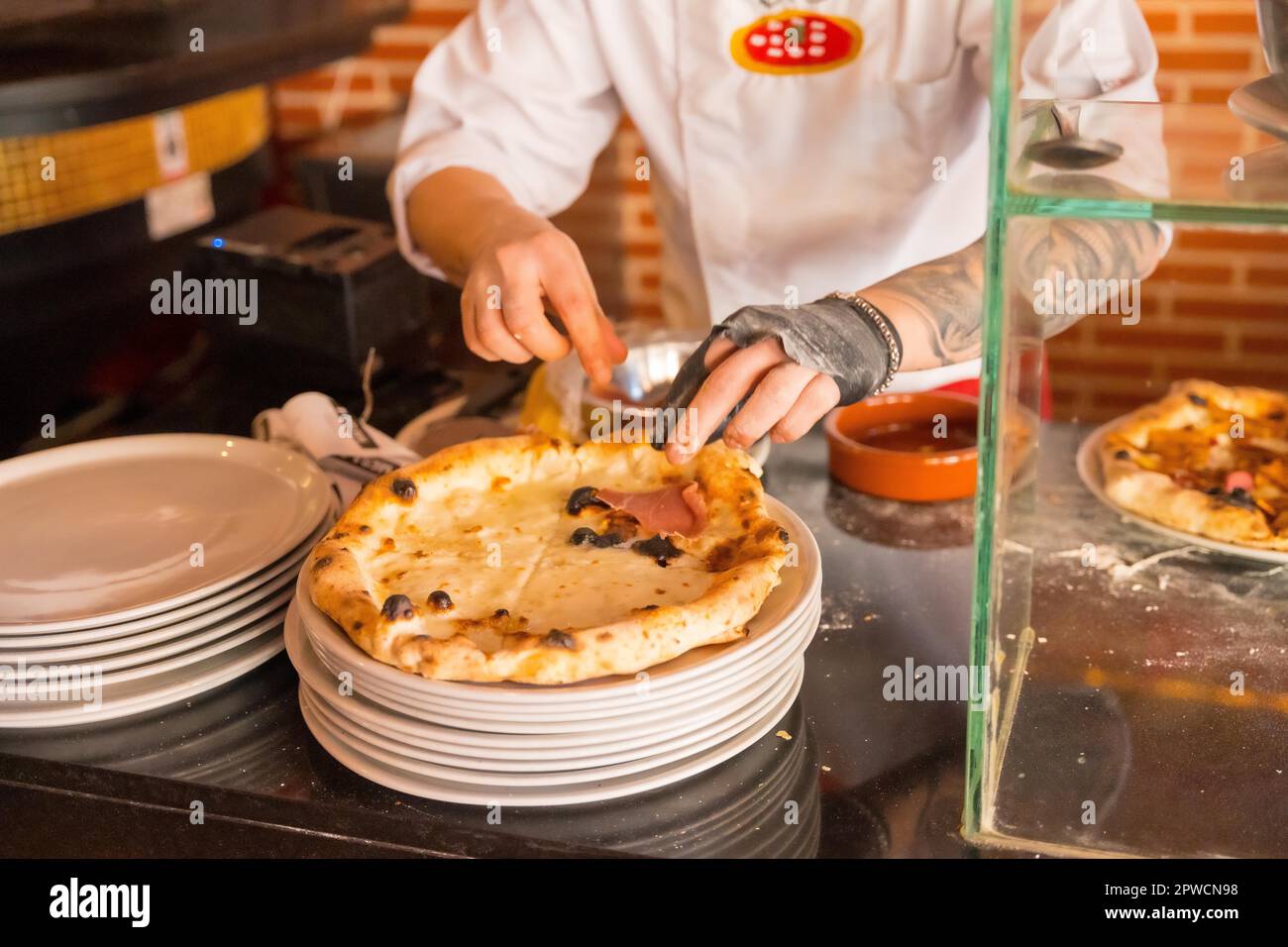 Artisan pizza oven. Chef preparing the pizza to sell it, pizza hot and ready for customers Stock Photo