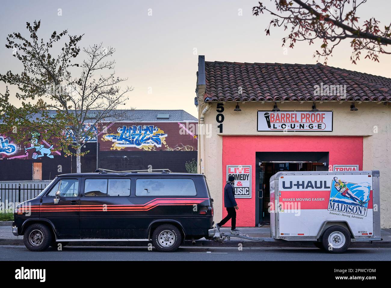 Man in dark clothing walking in front of Barrel Proof Lounge comedy