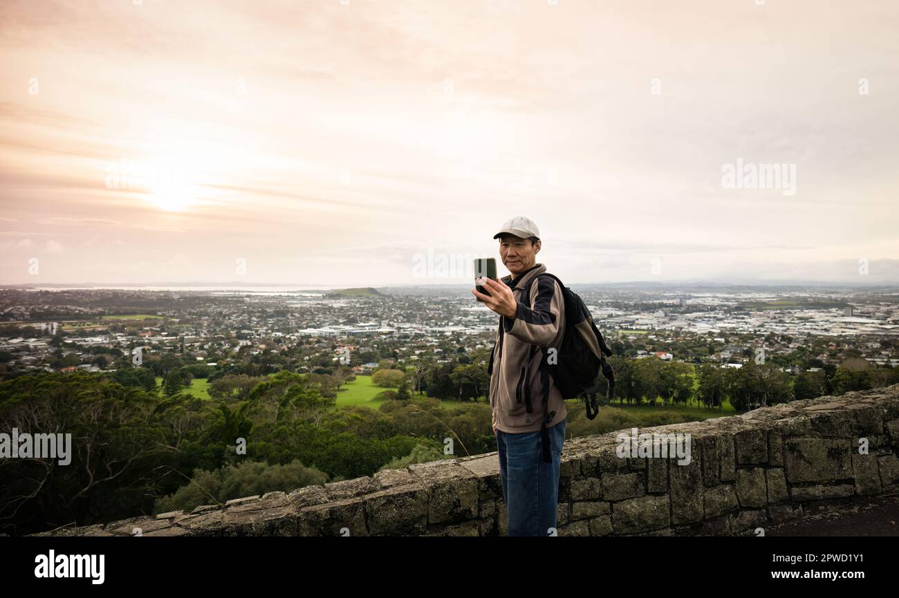 Tourist taking selfie photos with smartphone at One Tree hill. Auckland. Stock Photo
