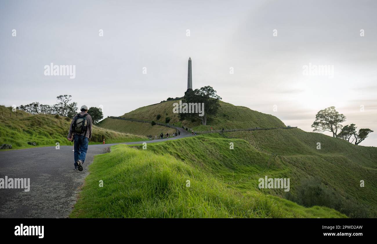 Man walking towards the Tower at One Tree Hill. Unrecognizable people walking in the distance. Auckland. Stock Photo