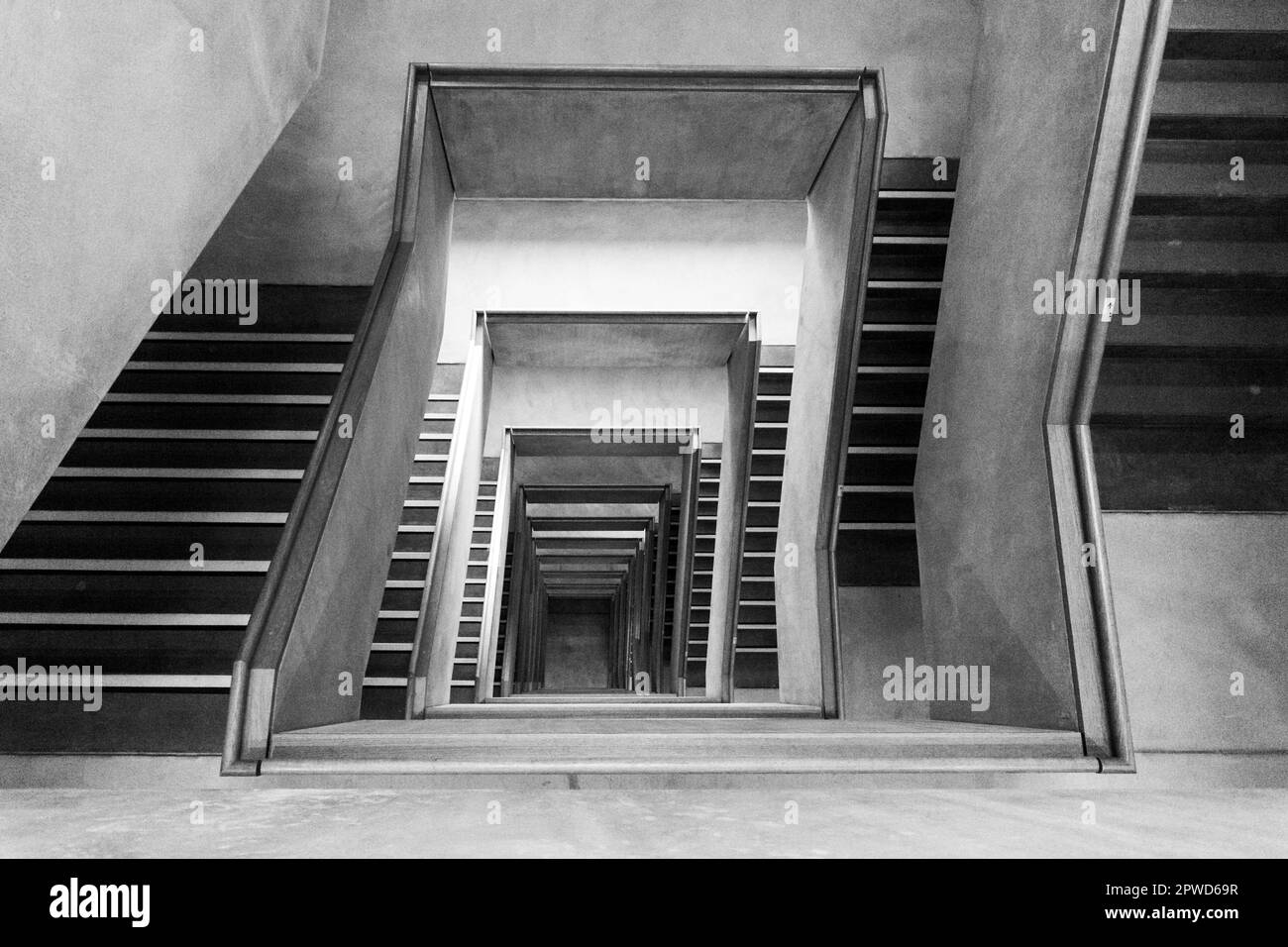 Contemporary concrete staircase with wooden handrail as viewed from the top floor Stock Photo