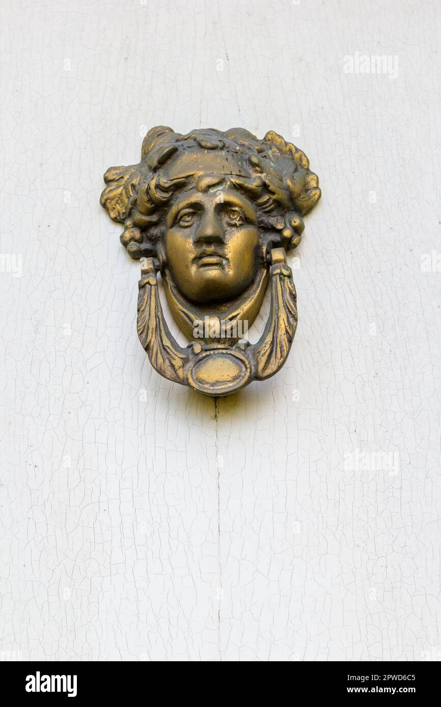 Door knocker or knob with a victorian face on the white painted wood