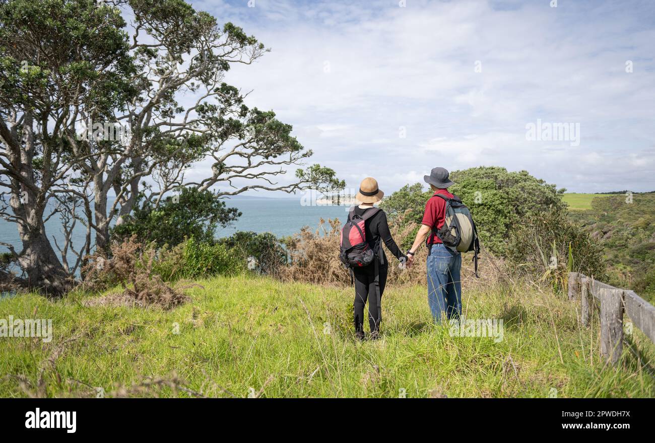 Couple holding hands, enjoying beautiful views of Hauraki Gulf. Long Bay coastal walk. Auckland. Stock Photo