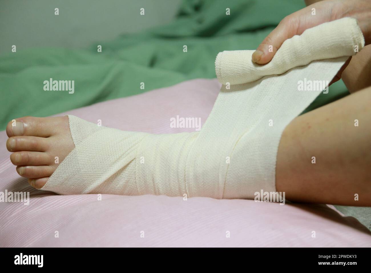 Concept of bandaging and treating an ankle injury at home Stock Photo