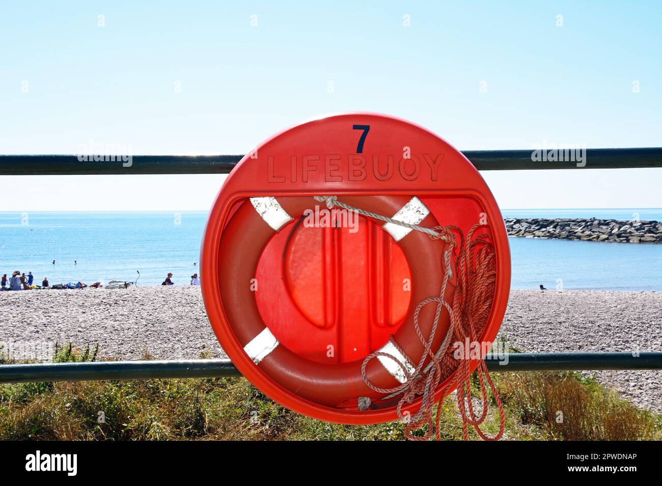Lifebuoy ring attached to the railings at the edge of the beach with views out to sea, Sidmouth, Devon, UK, Europe. Stock Photo