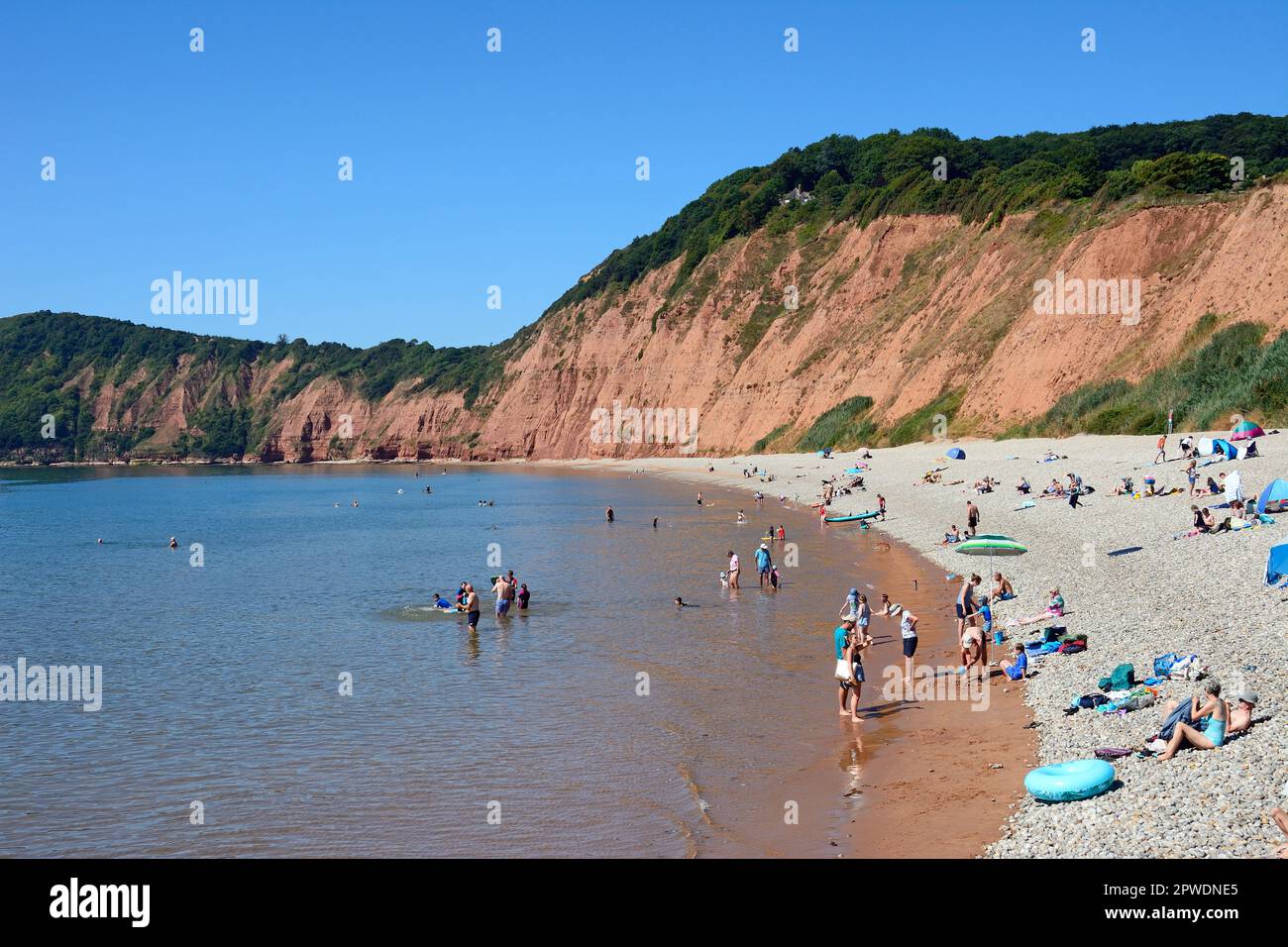 Tourists relaxing on Jacobs Ladder beach with views towards the cliffs, Sidmouth, Devon, UK, Europe. Stock Photo