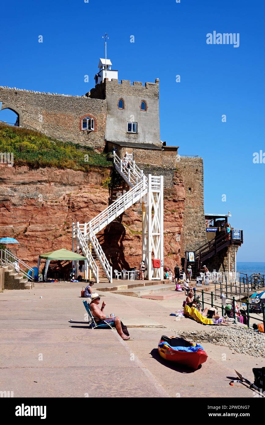 Tourists relaxing on Jacobs Ladder beach with the castle on the hillside, Sidmouth, Devon, UK, Europe. Stock Photo