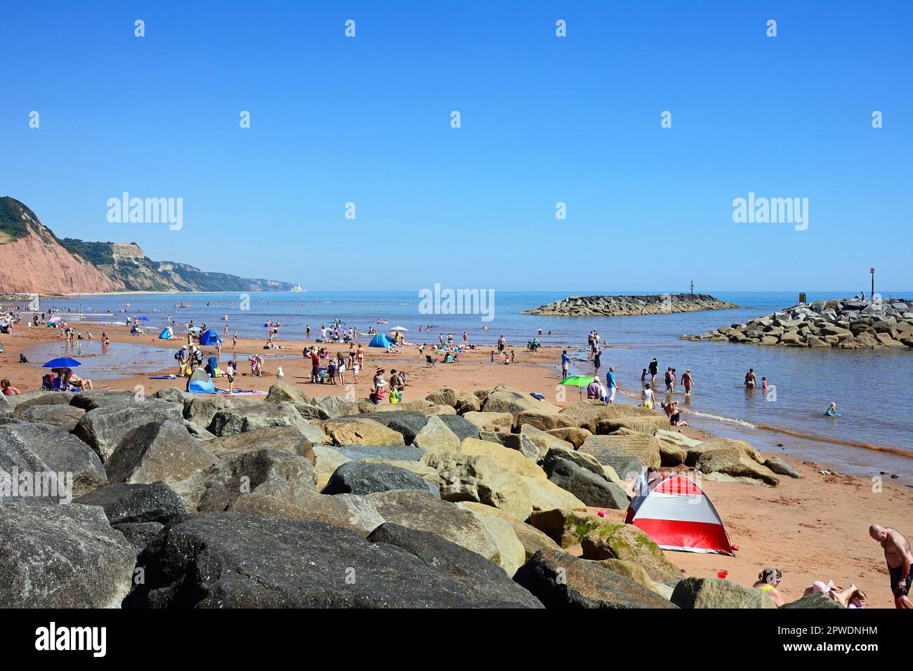 Tourists relaxing on the beach with views towards the cliffs at Pennington Point, Sidmouth, Devon, UK, Europe. Stock Photo