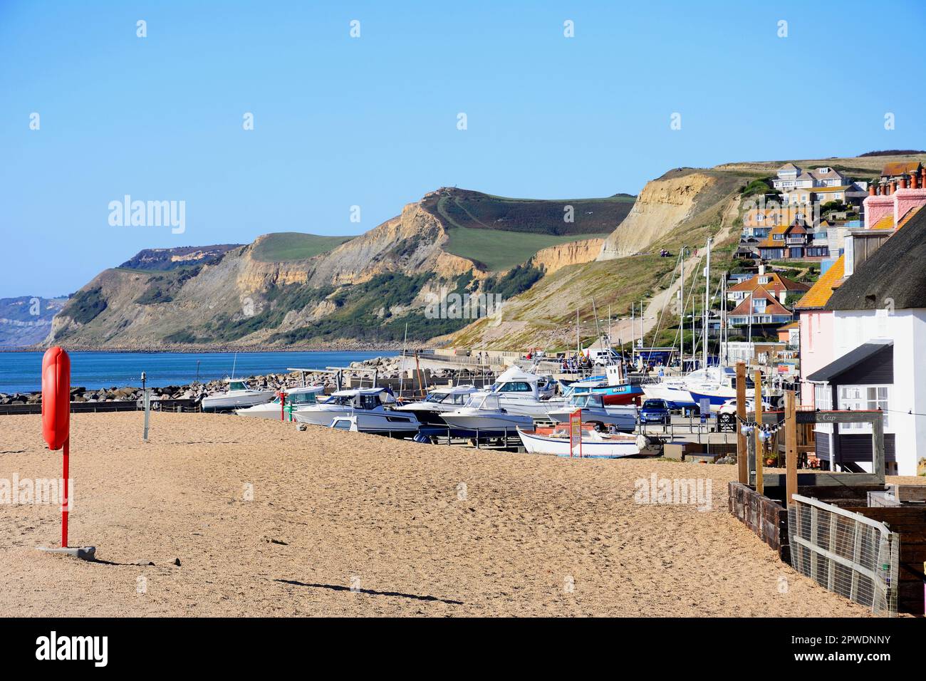 View looking West towards the beach and cliffs with boats in dry dock in the foreground, West Bay, Dorset, UK, Europe. Stock Photo