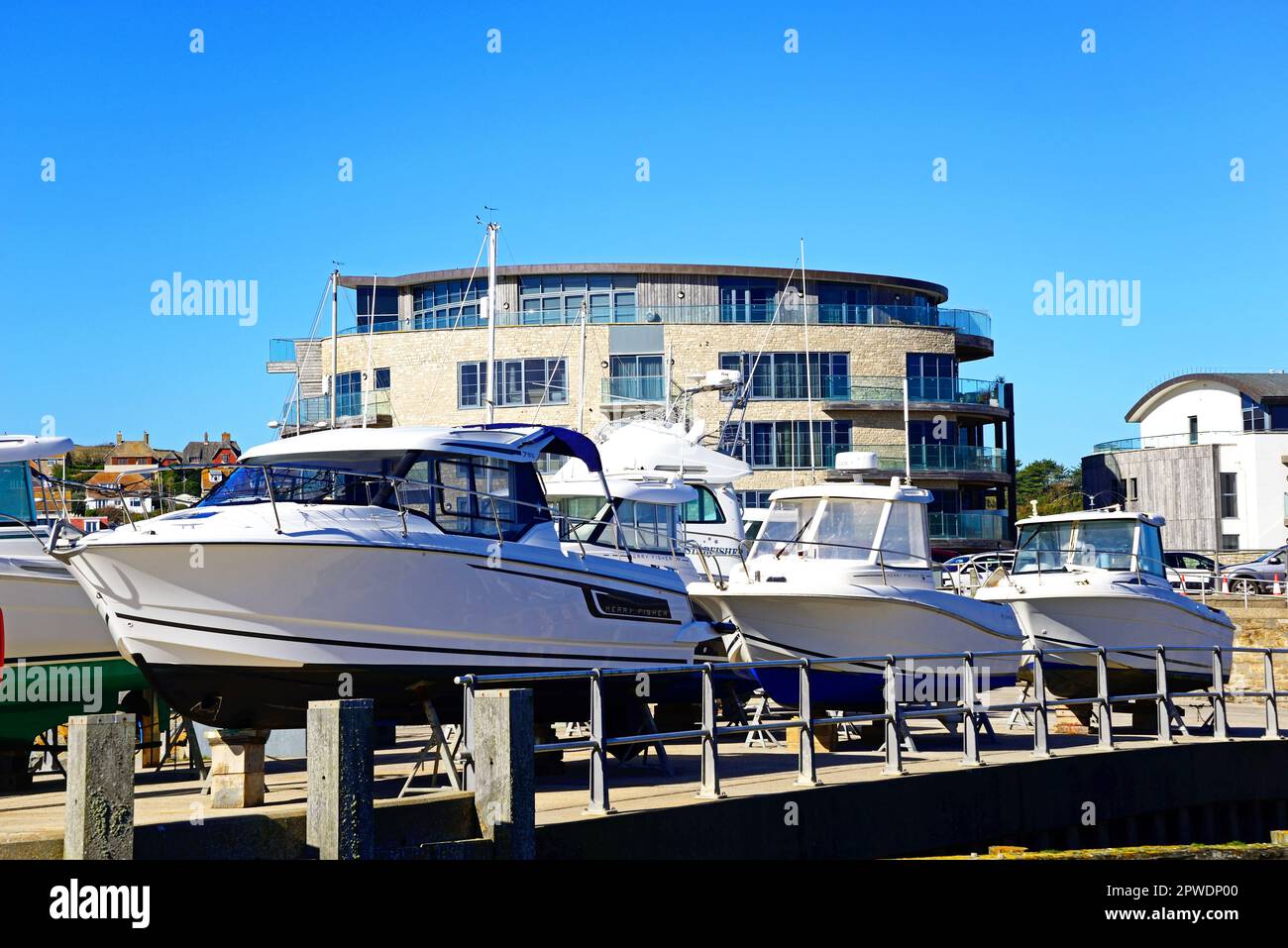 Boats in dry dock with the Ellipse building and along the quayside to the rear, West Bay, Dorset, UK, Europe. Stock Photo