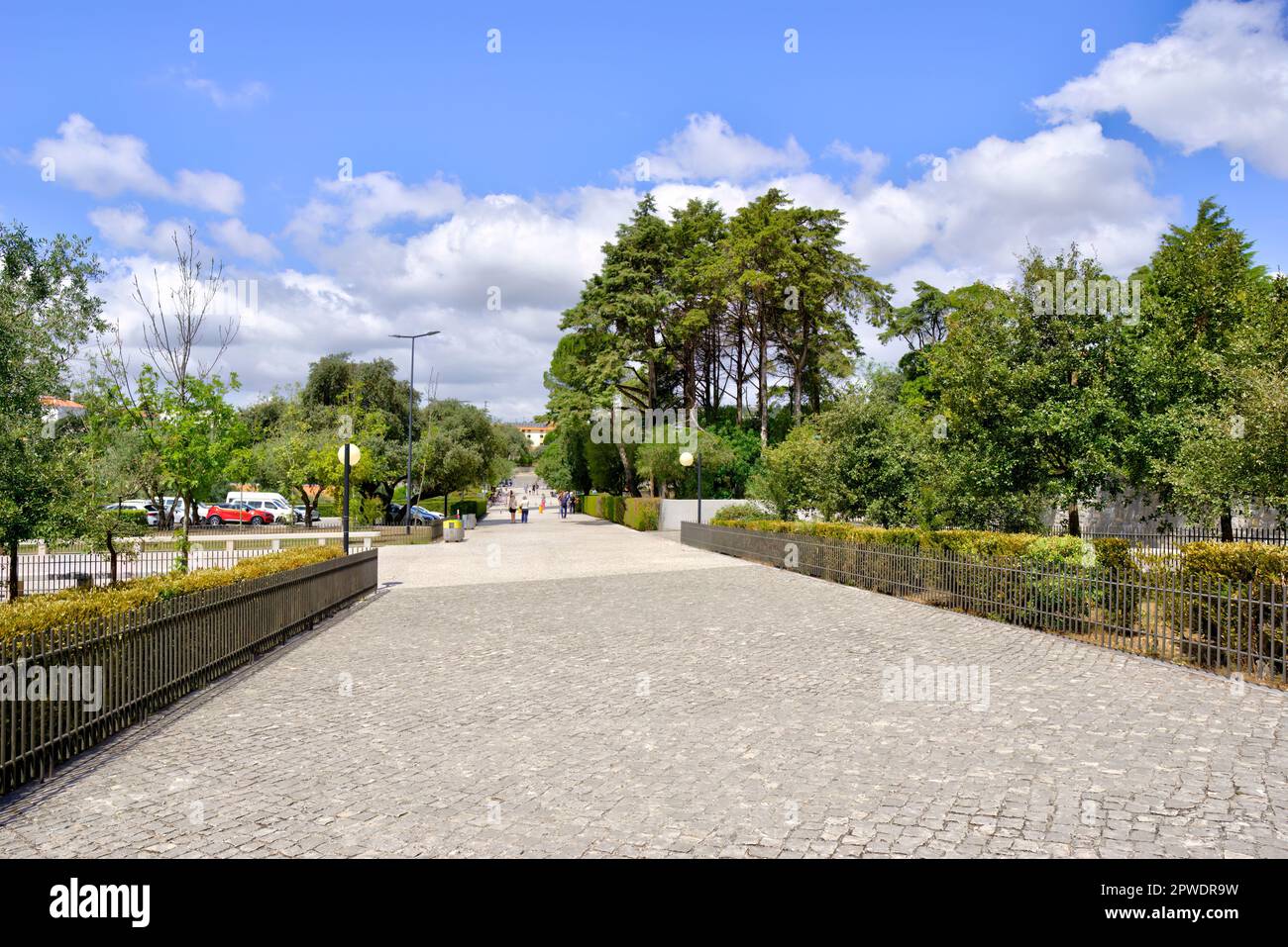 Fatima, Portugal - August 15, 2022: Access path with trees and bushes surrounding cobble stone path Stock Photo