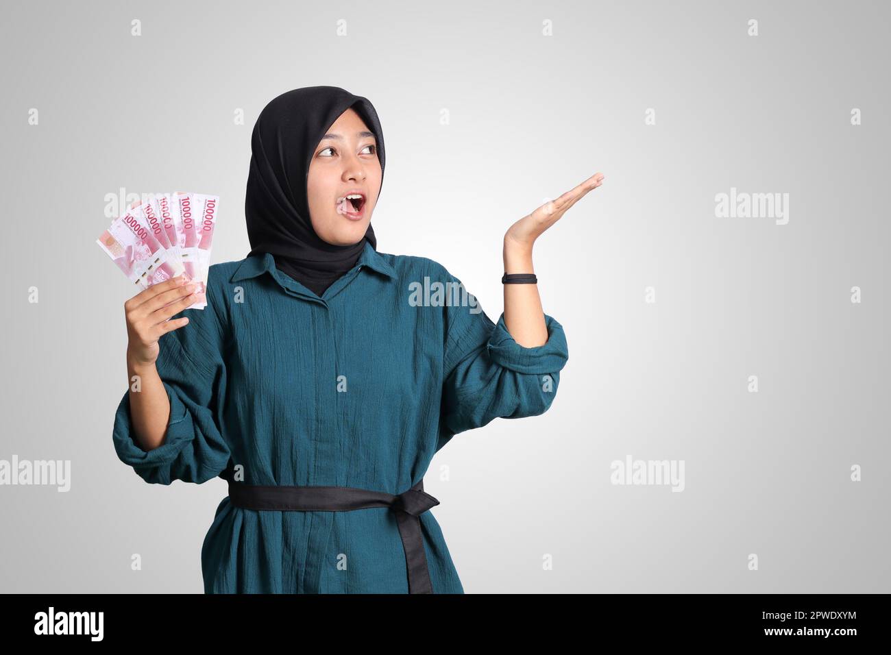 Portrait of excited Asian hijab woman in casual outfit showing and ...